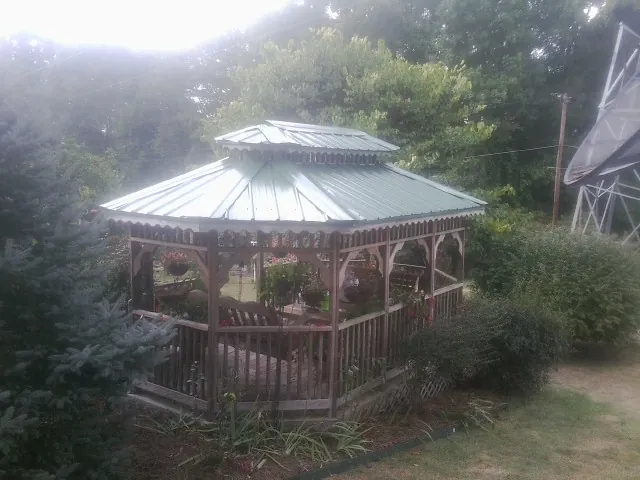 Green metal roof on a backyard gazebo surrounded by garden beds in Odessa